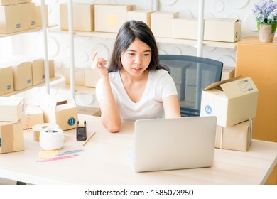 Small business owner, woman checking purchase order in laptop and write in the delivery on package box - sell online or online shopping concept - Shutterstock ID 1585073950