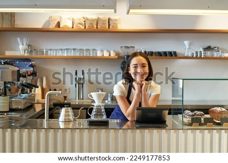 Small business owners. Smiling asian girl barista, standing at counter with filter coffee brewing kit and POS terminal, cafe and people concept.