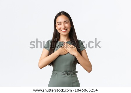 Small business owners, women entrepreneurs concept. Touched and pleased asian businesswoman receive award, being praised or receive compliment, holding hands on heart, smiling broadly
