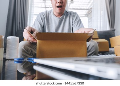 Small Business Parcel For Shipping, Happy Man Opening Online Shopping Package Box With Parcel While Sitting On Sofa At Home.