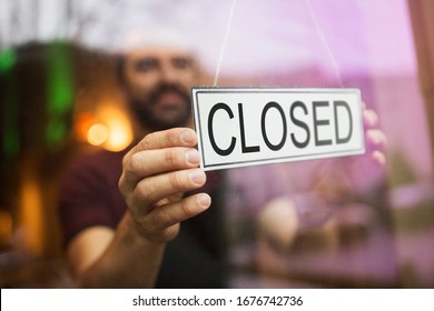small business, people and crisis concept - owner puts closed sign at bar or restaurant glass door or window