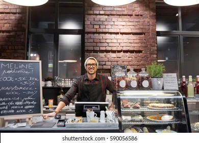 Small Business, People And Service Concept - Happy Seller Man Or Barman At Counter With Cashbox In Vegan Cafe Or Coffee Shop