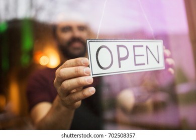 small business, people and service concept - man with open word on banner at bar or restaurant window