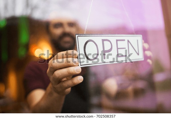 small business, people and\
service concept - man with open word on banner at bar or restaurant\
window