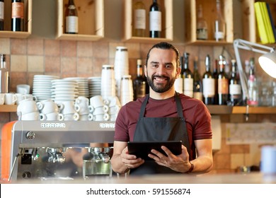 small business, people, technology and service concept - happy man or waiter in apron with tablet pc computer at bar or coffee shop