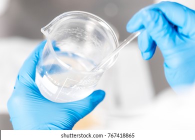 Small business people at work. Working process in laboratory of cosmetic production. Mixing components. Close-up hands of technologist making face care creams.