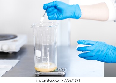 Small business people at work. Working process in laboratory of cosmetic production. Mixing components. Close-up hands of technologist making face care creams.