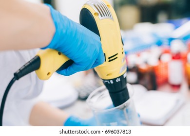 Small business people at work. Young woman working at the laboratory of cosmetic production. Hand with mixer.