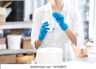 Small business people at work. Young woman working at the laboratory of cosmetic production. Mixing ingredients. Young technologist making face care creams. Private small cosmetic products factory.