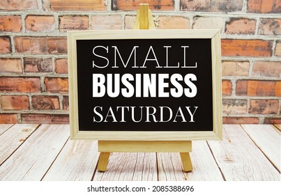 Small Business Saturday Typography Text On The Blackboard Set On Wooden Floor And Brick Background