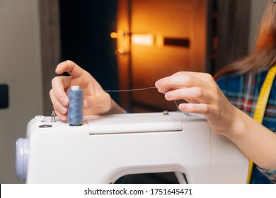 Small business seamstresses, making clothes in his apartment, home workshop. Girl inserts thread into sewing machine, closeup, - Shutterstock ID 1751645471