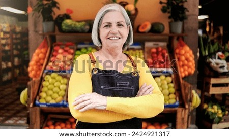 Small business senior woman outside farmer market looking at camera. Latin American owner working at supermarket vegetable store