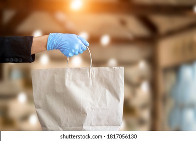 Small business and service concept with young woman Wearing blue gloves Filed paper bag with take away drink in cafe