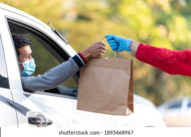 Small business and service concept with young man Wearing blue gloves Holding a paper bag to the customer with Drive in take away