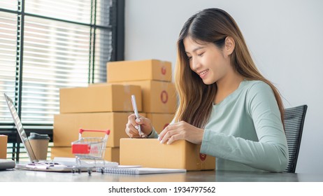  Small Business Startup Freelance SME Entrepreneurs Beautiful Asian Young Women Working at Home with Box, Smartphone, Laptop on the Table with Online Sales, Marketing, Packaging, SME Shipping, Ecommer