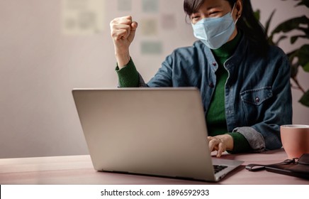 Small Business And Successful During Coronavirus Concept. Blurred Gladful Business Woman Wearing Mask, Working On Computer Laptop In Office. Focus On Hand. Business Achieves Goals. Celebrating Success