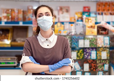 Small Businesses During The Pandemic.Portrait Of A Female Worker In A Medical Mask And Gloves Posing With Her Arms Crossed.Grocery Store On The Background.Concept Of Protection Against Coronavirus