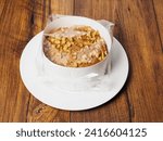 Small cake with nuts in plastic wrap on wooden board. Premium high quality dessert products. Tasty snack