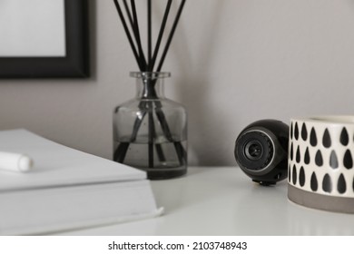 Small Camera Hidden Among Home Stuff On White Table Indoors