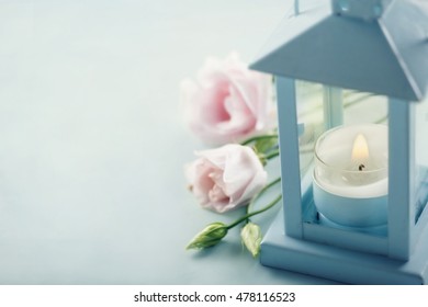 Small candle in a blue lantern with pink flowers - condolences concept