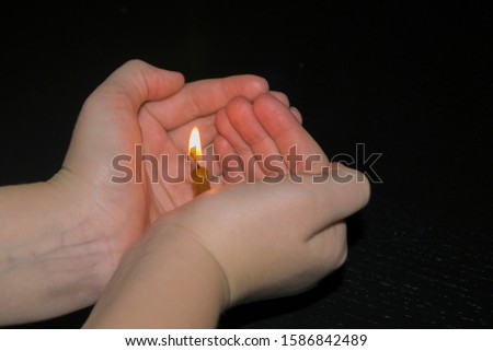 a small candle burns in  hands in the night