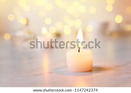 Small candle with light yellow spots on light background