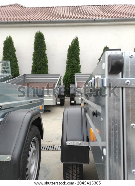 Small car open trailers in a shop for rental and\
sales. Grey new trailers