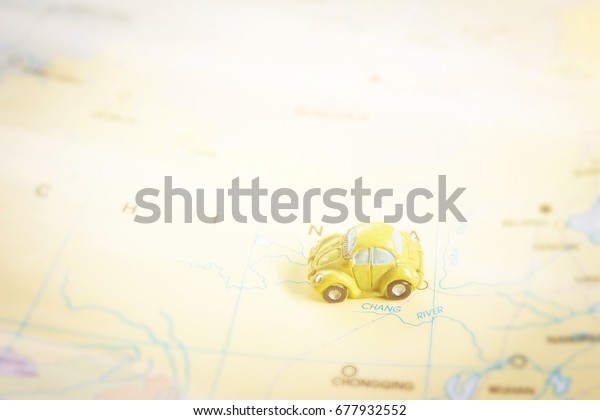 Small car toy on map with bright light, travel and\
journey concept 