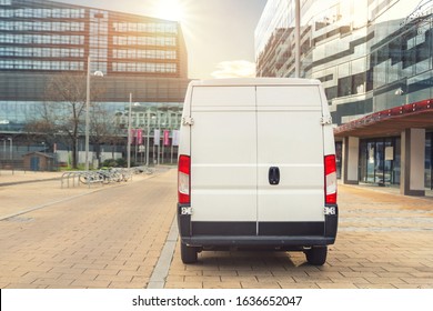 Small cargo delivery van driving in european city central district. Medium lorry minivan courier vehicle deliver package at residential office building in downtown area. Commercial shipping logistics.