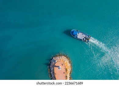 Small cargo ship sails through blue sea to serve fish farm, aerial top view. - Powered by Shutterstock