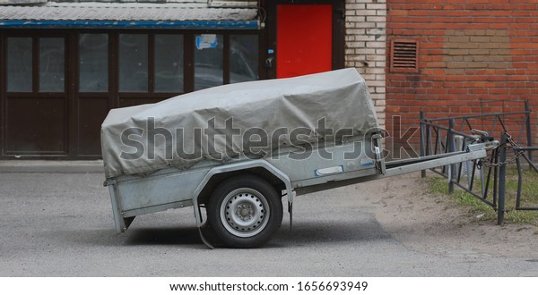 A\
small cargo trailer for a car strapped to the fence, prospekt\
Bolshevikov, Saint Petersburg, Russia, February\
2020
