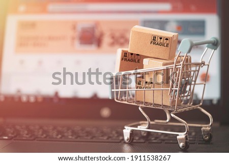 Small Cartons box with shopping trolley on computer laptop for online shopping concept.