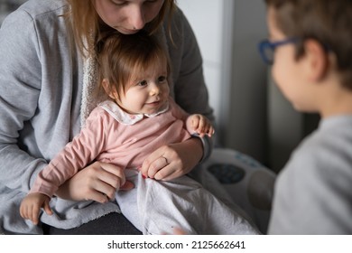 Small Caucasian Baby Getting Dressed Mother Young Woman Hold Her Child Daughter Girl While Dressing Her At Home Changing Clothes With Brother Boy Having Fun Real People Family Domestic Life Concept