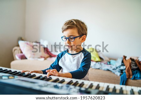 Small caucasian boy playing electric piano making music at home leisure activity growing up education and art concept playful child having fun at home alone