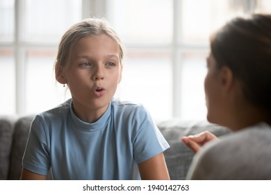 Small Caucasian teen girl child do articulation exercises with caring mother or teacher at home. Little kid pronounce sounds speak talk with tutor or coach, engaged in voice pronunciation together.