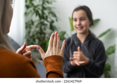 Small Caucasian teen girl child do articulation exercises with caring mother or teacher at home. Little kid pronounce sounds speak talk with tutor or coach, engaged in voice pronunciation together