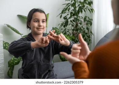 Small Caucasian teen girl child do articulation exercises with caring mother or teacher at home. Little kid pronounce sounds speak talk with tutor or coach, engaged in voice pronunciation together - Powered by Shutterstock