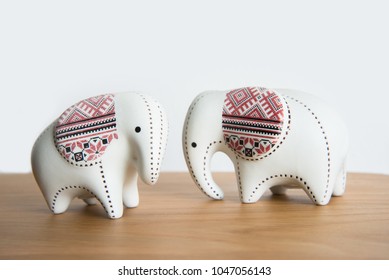Small ceramic elephant on a wooden floor on a white background.