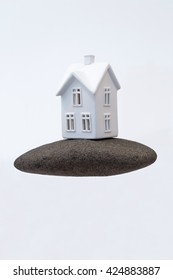 A Small Ceramic House On A Strong Foundation Of A Large Rock. Great For Concepts About Foundations, Home Purchasing, Insurance, Or Other Abstract Ideas. Vertical With Copy Space.