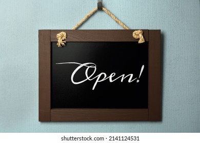 Small Chalk Board With Word Open On Light Blue Wall