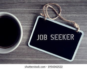 Small chalkboard on wood table with text JOB SEEKER ,refers to an individual looking for employment , seeking job, unemployed person trying to get hired or change the current work