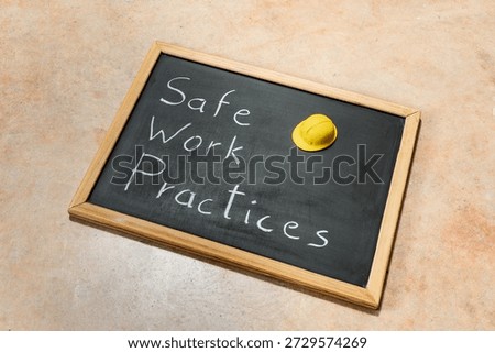 Small chalkboard with the text Safe Work Practices and yellow hard hat. Concepts of safety, precaution, and standards in the workplace.Blackboard on a cement background