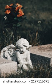 A Small Cherub Statue Sits In Between Two Graves. 