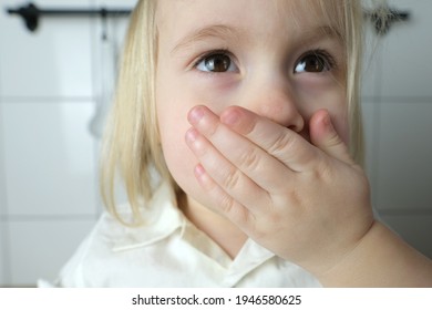 small child, baby, blonde girl covered her mouth with her palm, the concept of parenting, punishment for bad words, children's jokes, teasing - Shutterstock ID 1946580625