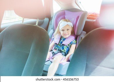 Small Child (blonde Girl) 4 Years In Car Seat Wearing Seat Belts Happy Is Going To Go In The Path Of The Road, Sun Glare Reflected