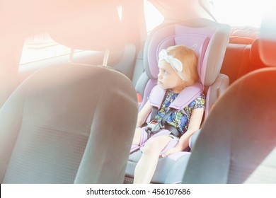 Small Child (blonde Girl) 4 Years In Car Seat Wearing Seat Belts Happy Is Going To Go In The Path Of The Road, Sun Glare Reflected