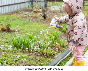 A Small Child Blows Soap Bubbles From A Gun