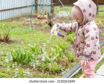 A Small Child Blows Soap Bubbles From A Gun