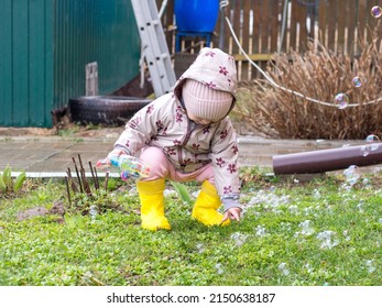 A Small Child Blows Soap Bubbles From A Gun