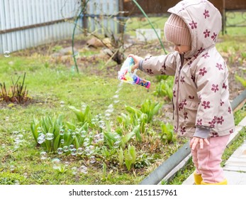 A Small Child Blows Soap Bubbles From A Gun